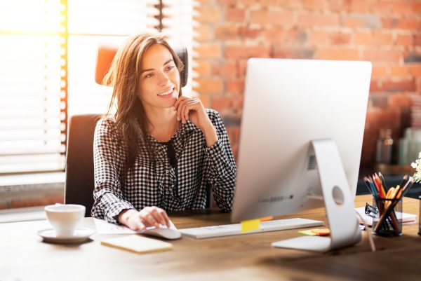 Woman working with computer at office. Smiling young employee business portrait.